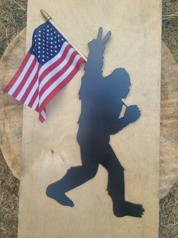 Bigfoot holding an American flag showing the peace sign.